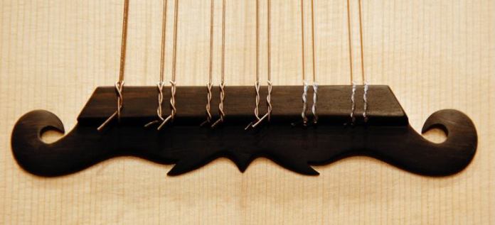 Der Knüpfsteg besteht aus Makassar-Ebenholz und überträgt die Saitenschwingung auf die Decke.